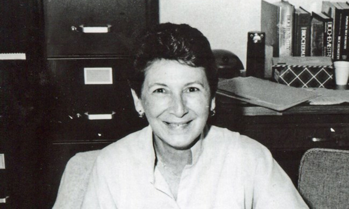 Casual, black and white portrait of a woman sitting at a desk in an office