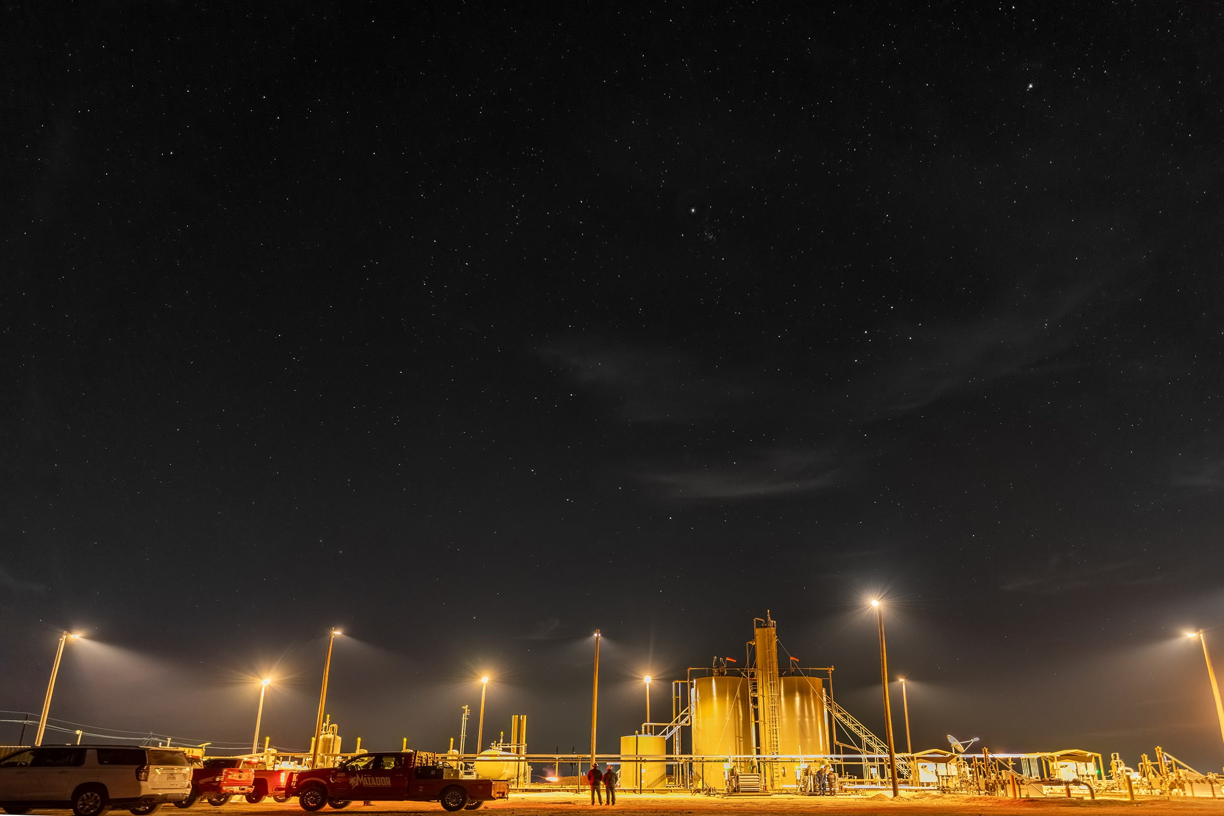 An oil and gas operation at night, bathed in amber light