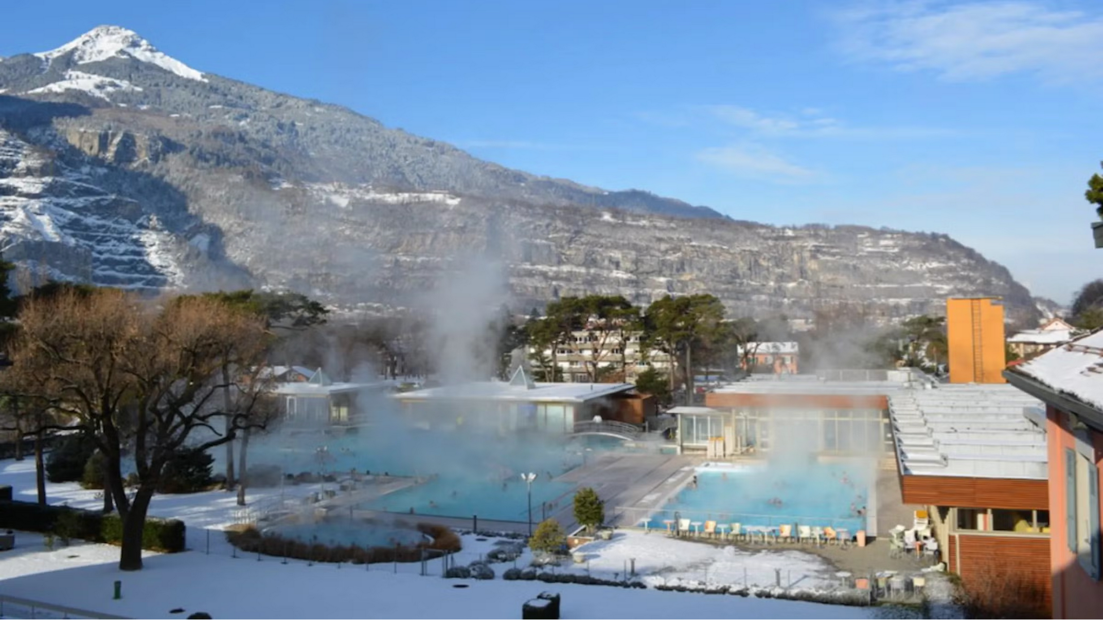 Steam rises from man-made pools in front of snow-capped mountains at a thermal spa in Switzerland