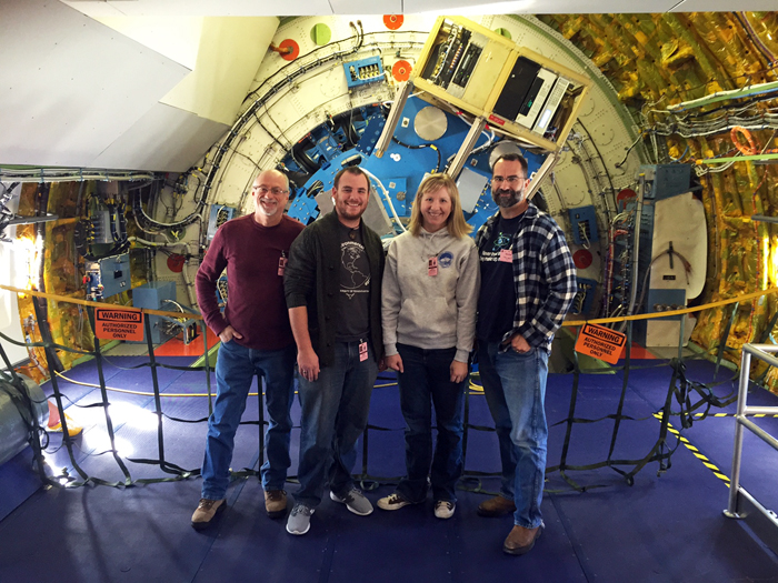 Four members of the team stand in front of the EXES instrument on board the SOFIA aircraft. They are, from left to right: Jeff Sralla, middle school teacher from Round Rock, Texas; Spencer Martin, a high school teacher from Manor, Texas; Dr. Keely Finkelstein, UT research associate and education team lead for the EXES Teacher Associate Program; and Dr. Tommy Greathouse, a research scientist at the Southwest Research Institute and an EXES Instrument science team member.