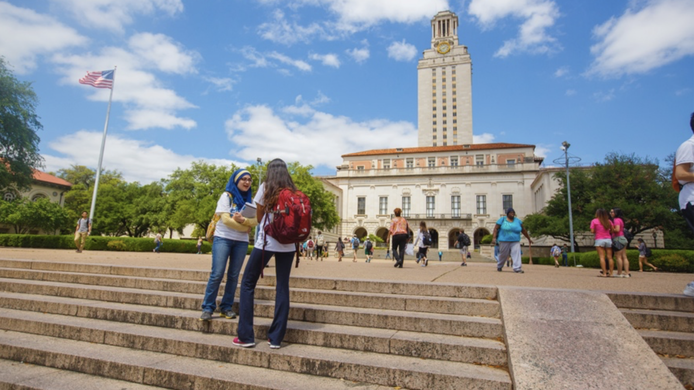 Two students talking on steps in front of the main administration building at the University of Texas at Austin