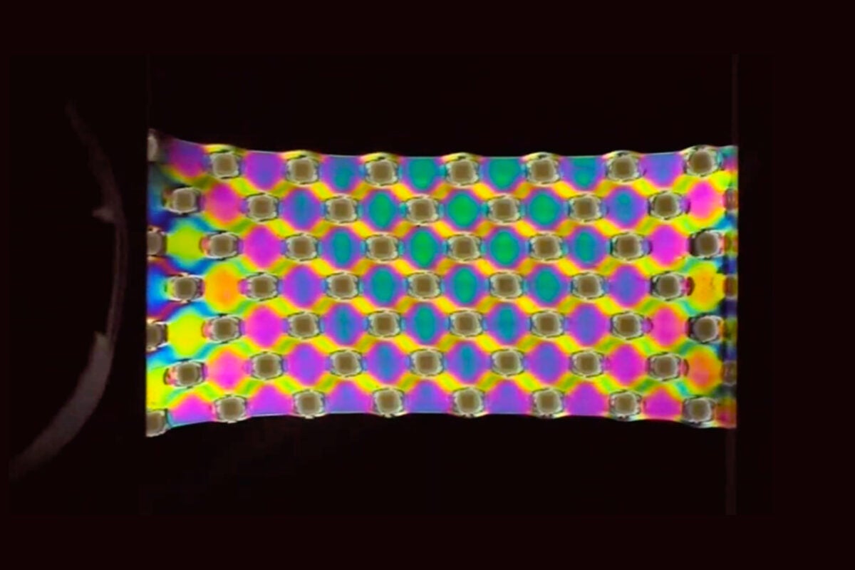 A strip of plastic with rainbow diamond pattern on a black ground