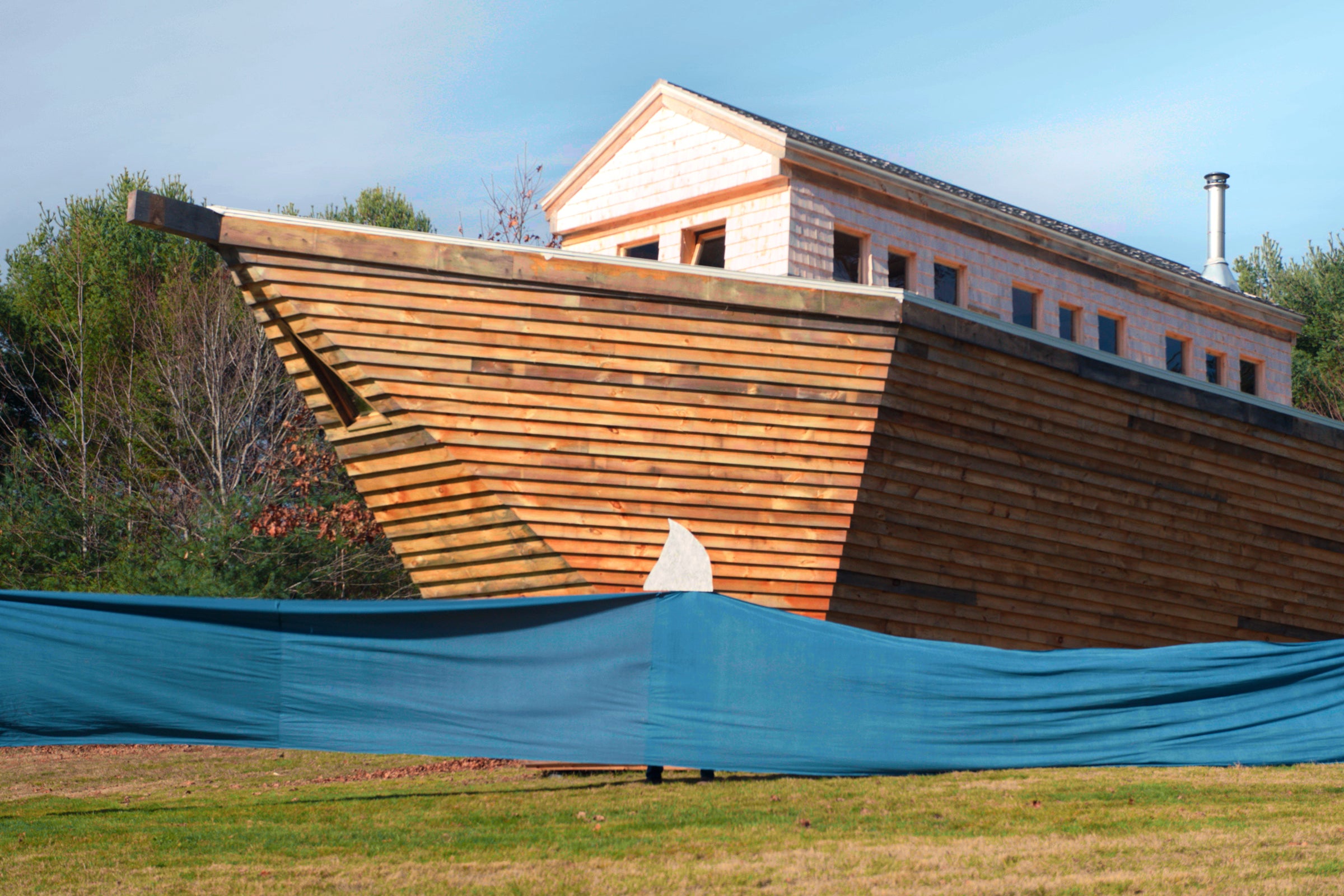 A wooden ark behind a blue tarp representing water