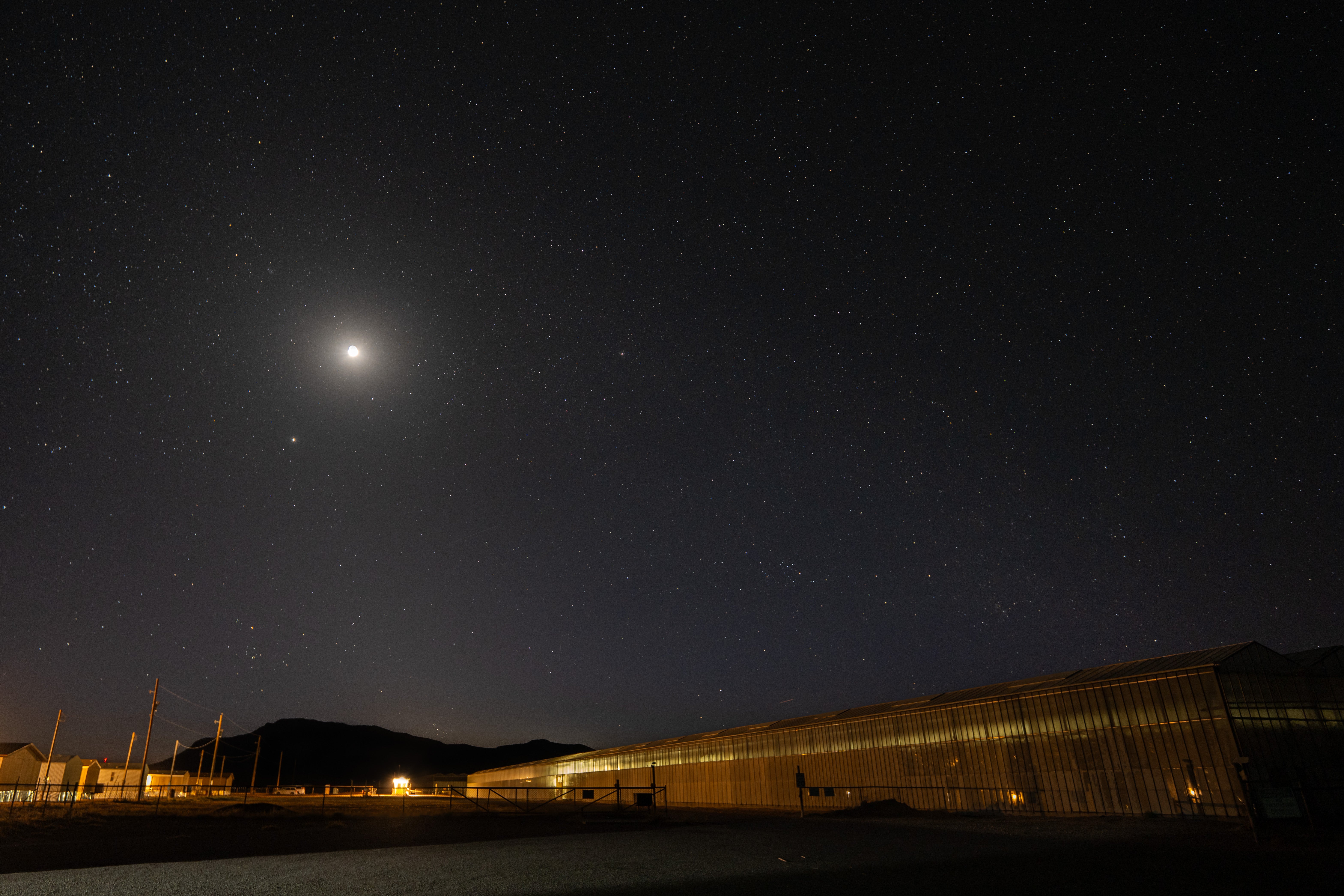 A photo of the dark night sky above greenhouses in West Texas.