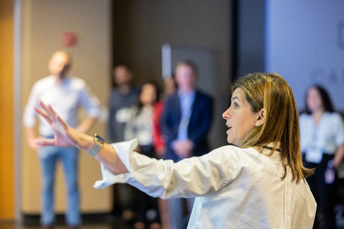 A scientist points to a pandemic model visualization in front of a standing audience