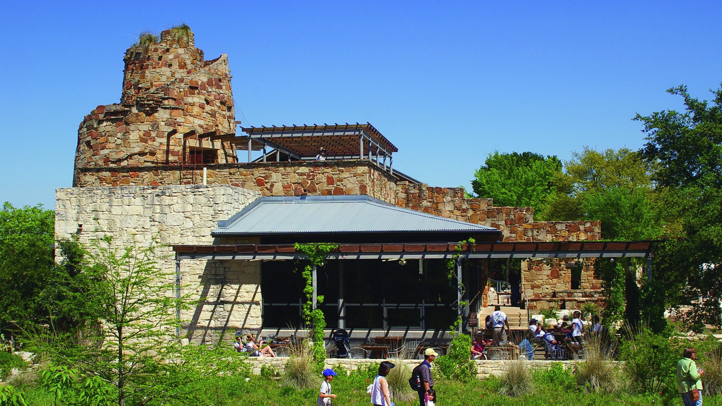 A building with a cafe and plants and visitors at the Wildflower Center