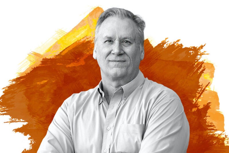 A man in a collared shirt is shown in black and white against a burnt orange designed backdrop